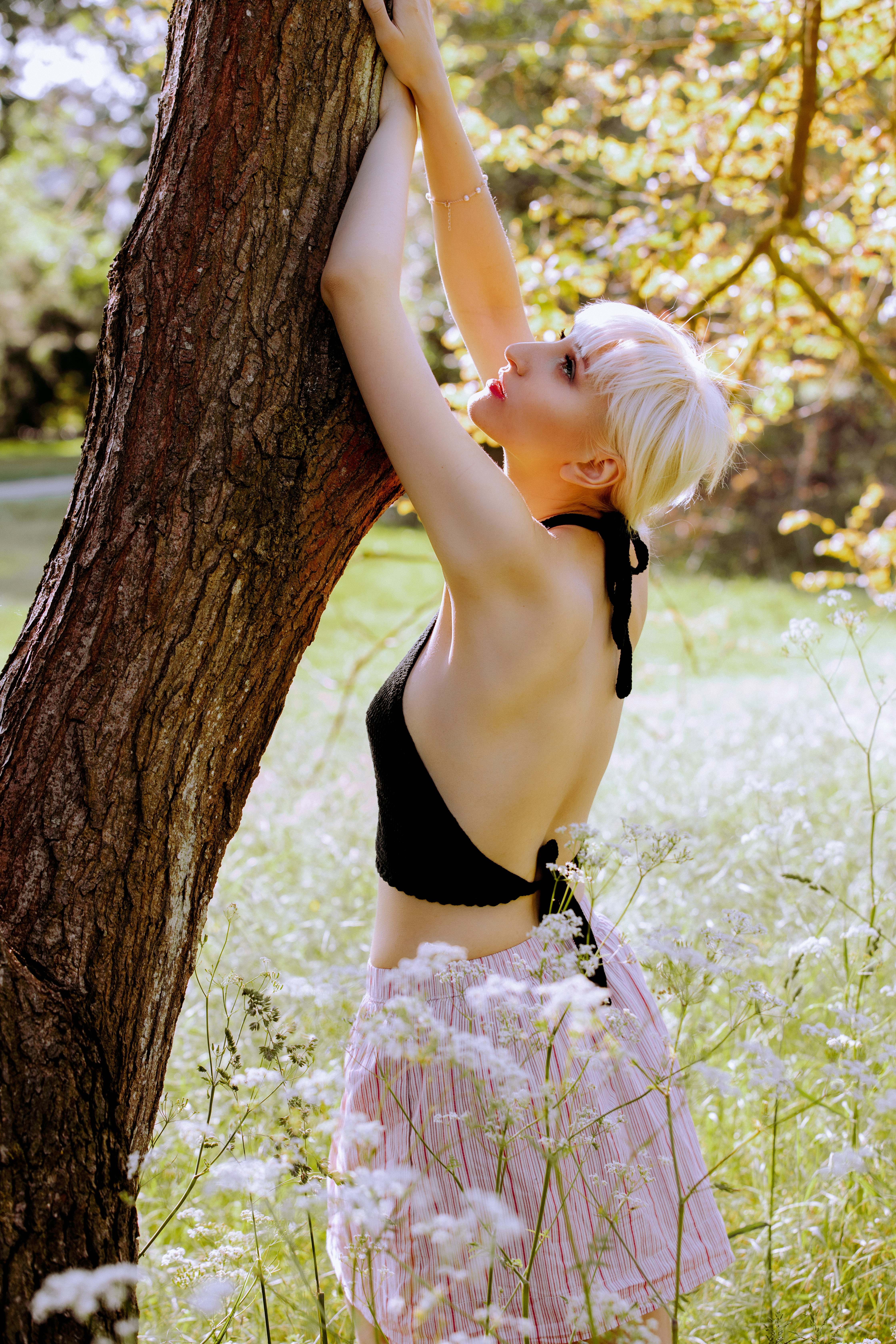 woman in black bikini leaning on brown tree trunk during daytime